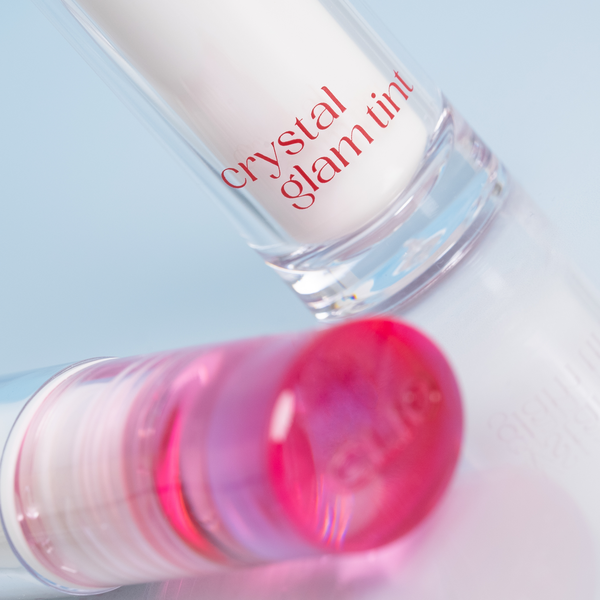 Clio Crystal Glam Lip Tint in a sleek tube, showcasing glossy, vibrant pink color with a shiny finish.