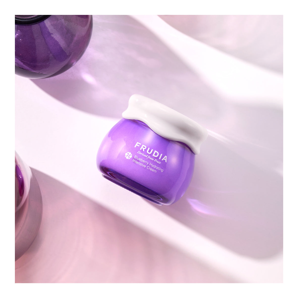 Frudia Blueberry Hydrating Intensive Cream face moisturizer in a jar with blue and white packaging, showcasing creamy texture.