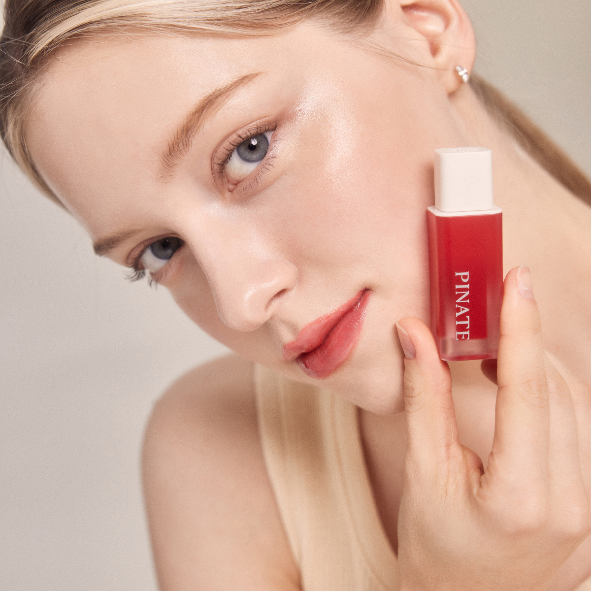 Pinate Natural Bloom Lip Oil Serum in clear lip gloss tube, featuring a shiny, nourishing lip gloss with natural plant extracts.