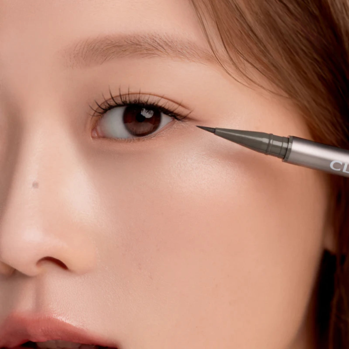Clio Superproof Brush Liner Kill Ash liquid eyeliner with precise brush tip and dark ash color on a white background.