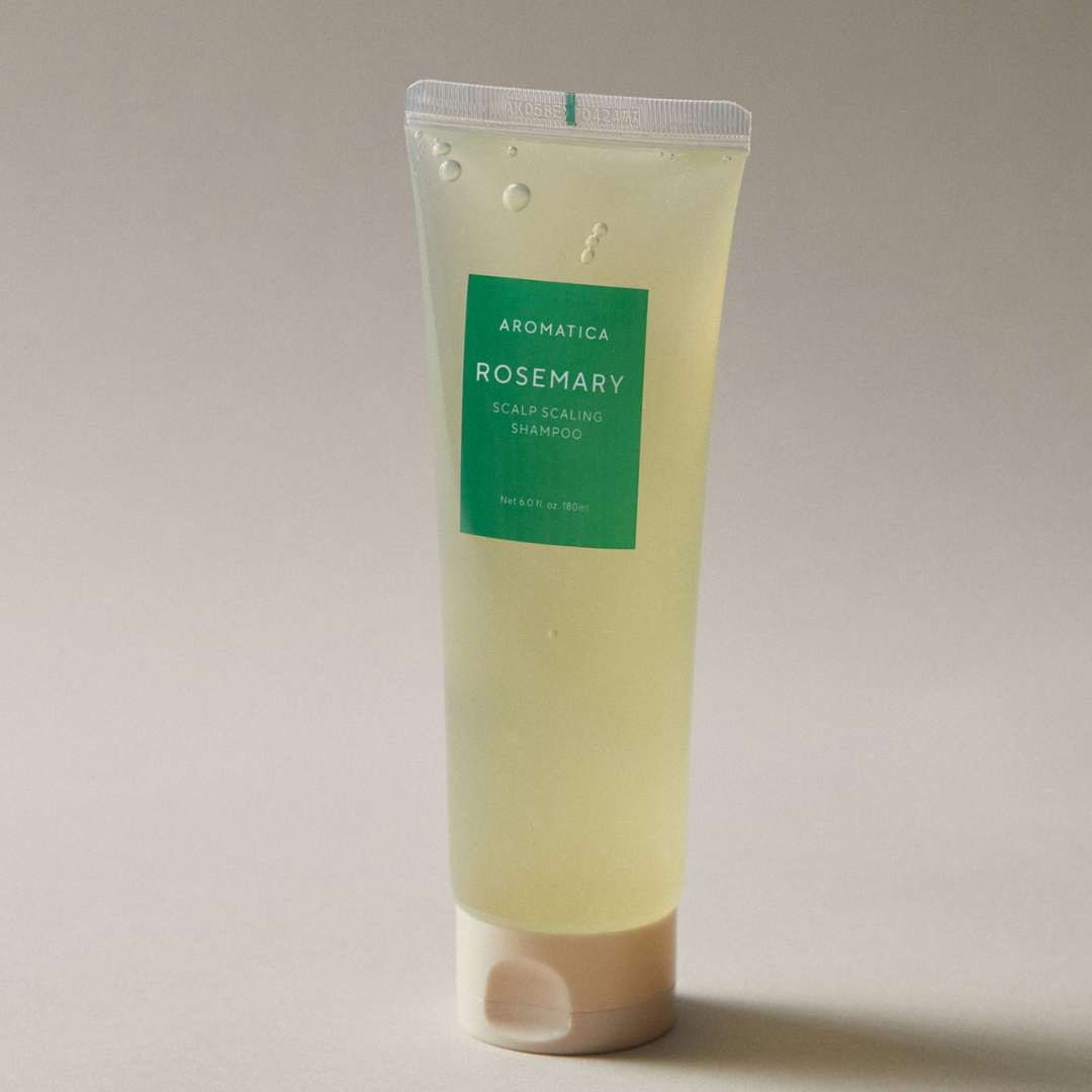 Aromatica Rosemary Scalp Scaling Shampoo bottle with rosemary leaves on a white background, highlighting natural hair care ingredients.
