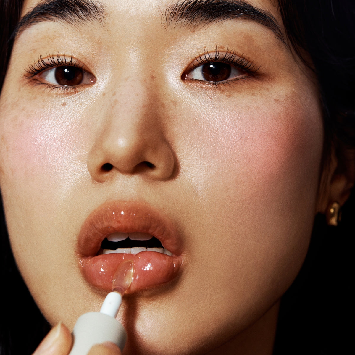 Unleashia Sisua Popcorn Syrup Lip Plumper tube with clear packaging and applicator, showcasing the lip enhancement product.