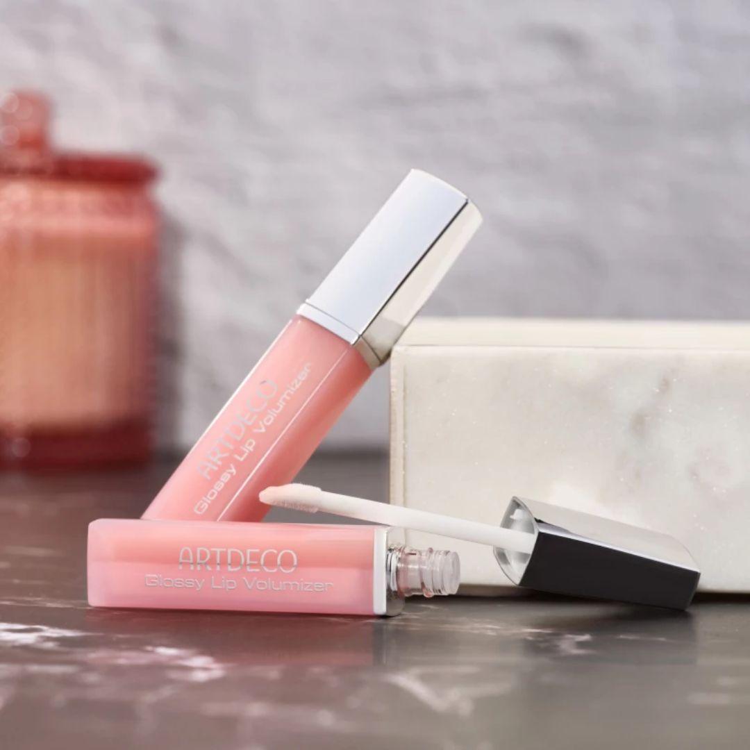 ARTDECO glossy lip volumizer in clear tube, showcasing a shiny lip plumper with a silver cap on a white background.