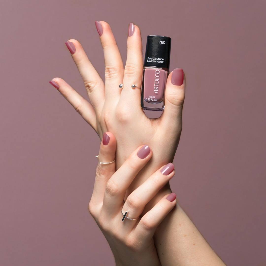 Artdeco Art Couture Nail Lacquer bottle with a glossy finish and colorful nail polish swatches in the background