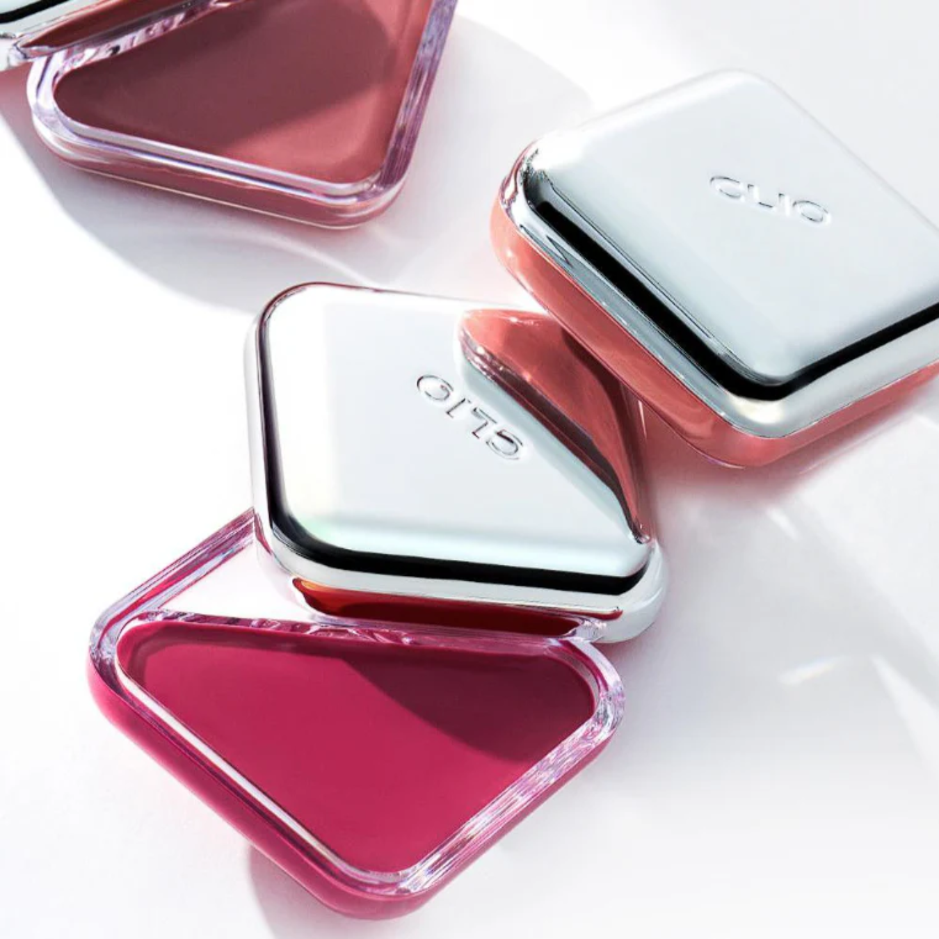 Clio Essential Lipcheek blush compact with soft pink and peach shades, open to show the pressed powder blush inside.
