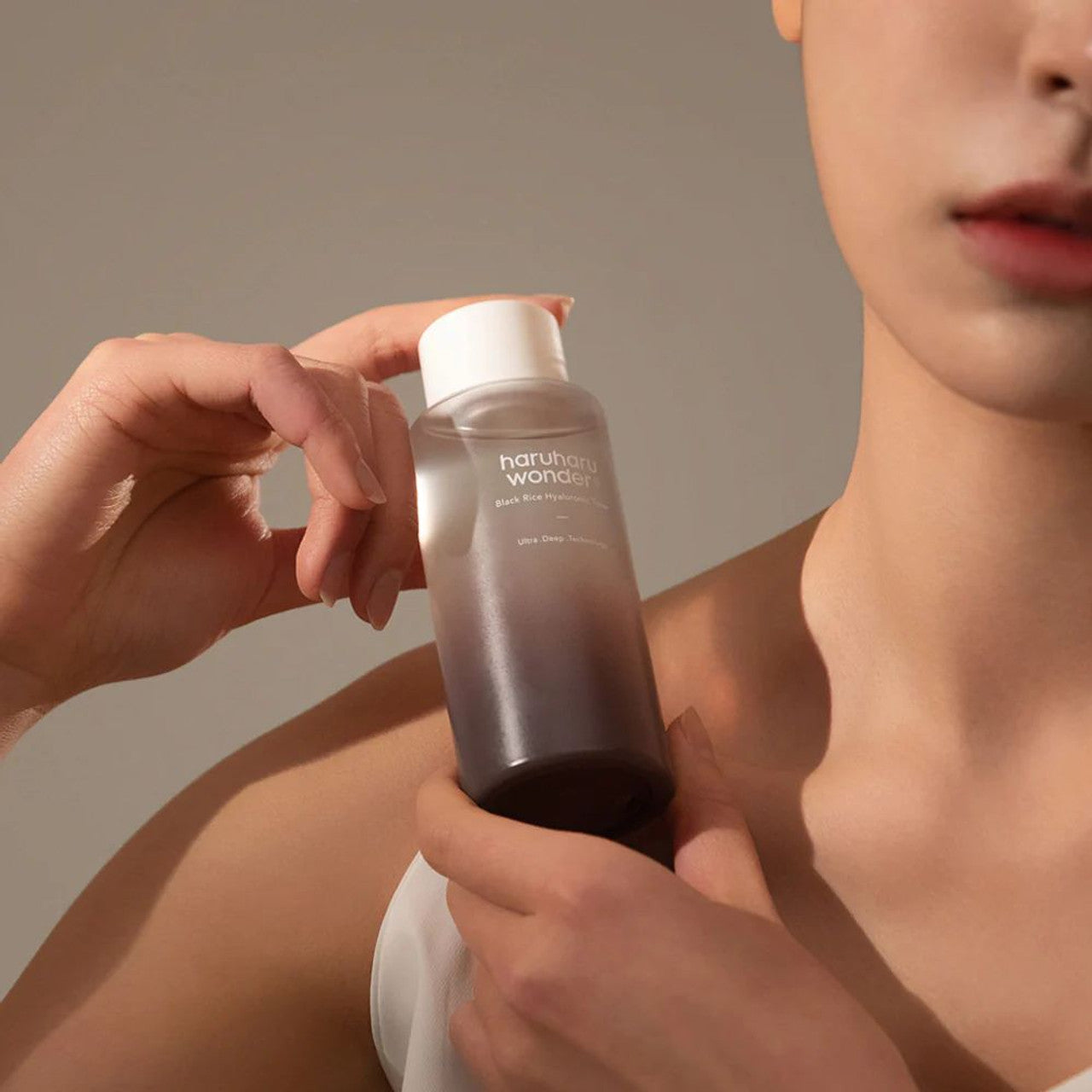 Model holding Haruharu Wonder Black Rice Hyaluronic Toner in 300ml bottle, showcasing the product for skincare and hydration.
