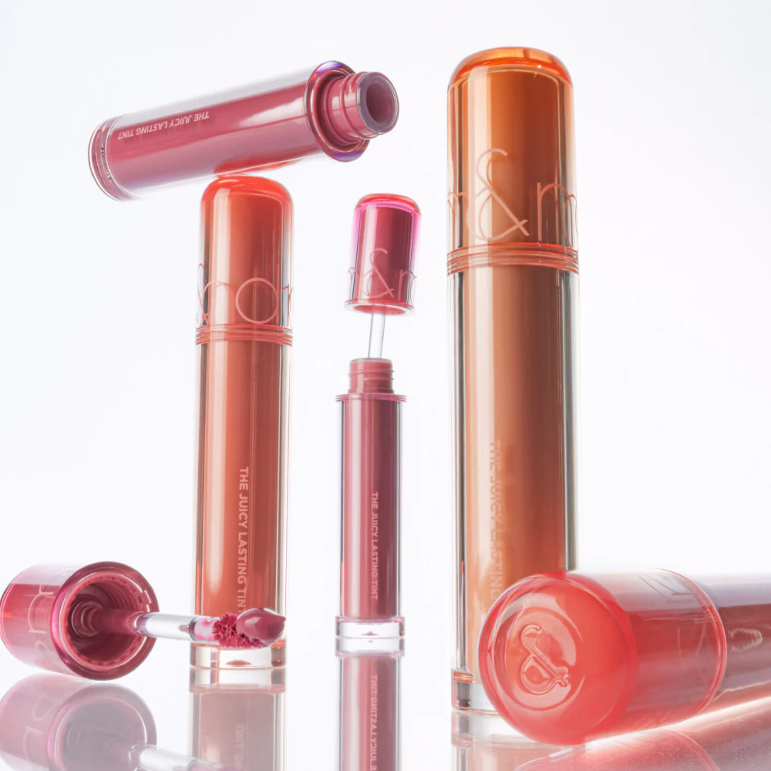Rom&nd Juicy Lasting Tint lip tint in a vibrant shade, showing the product tube and applicator against a neutral background.