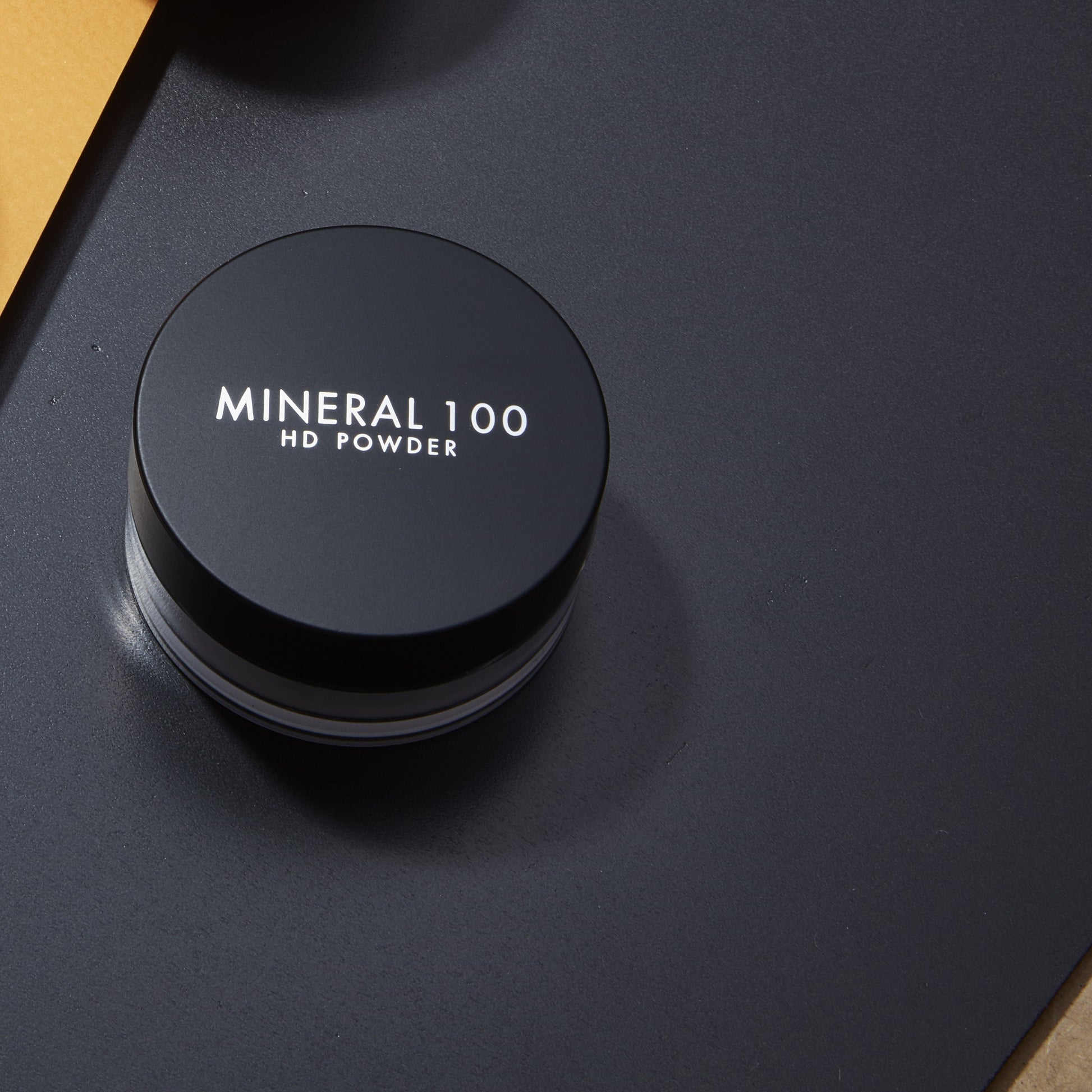 A'pieu Mineral 100 HD Powder setting powder in a sleek compact, showcasing its fine, translucent texture for flawless makeup setting.
