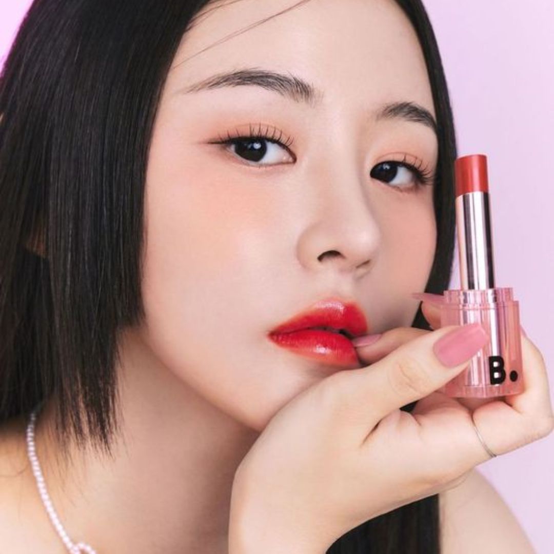 Banila Co B. By Banila Glow Veil Lipstick in shade RD02, showing a sleek lipstick tube with the product partially opened.