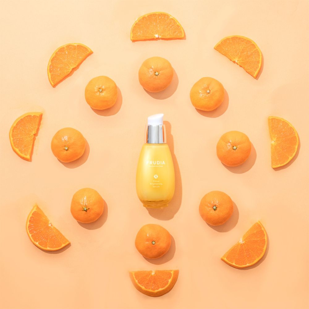 Frudia Citrus Brightening Serum 50g in a clear glass bottle with a pump, featuring a citrus-themed label and bright packaging.