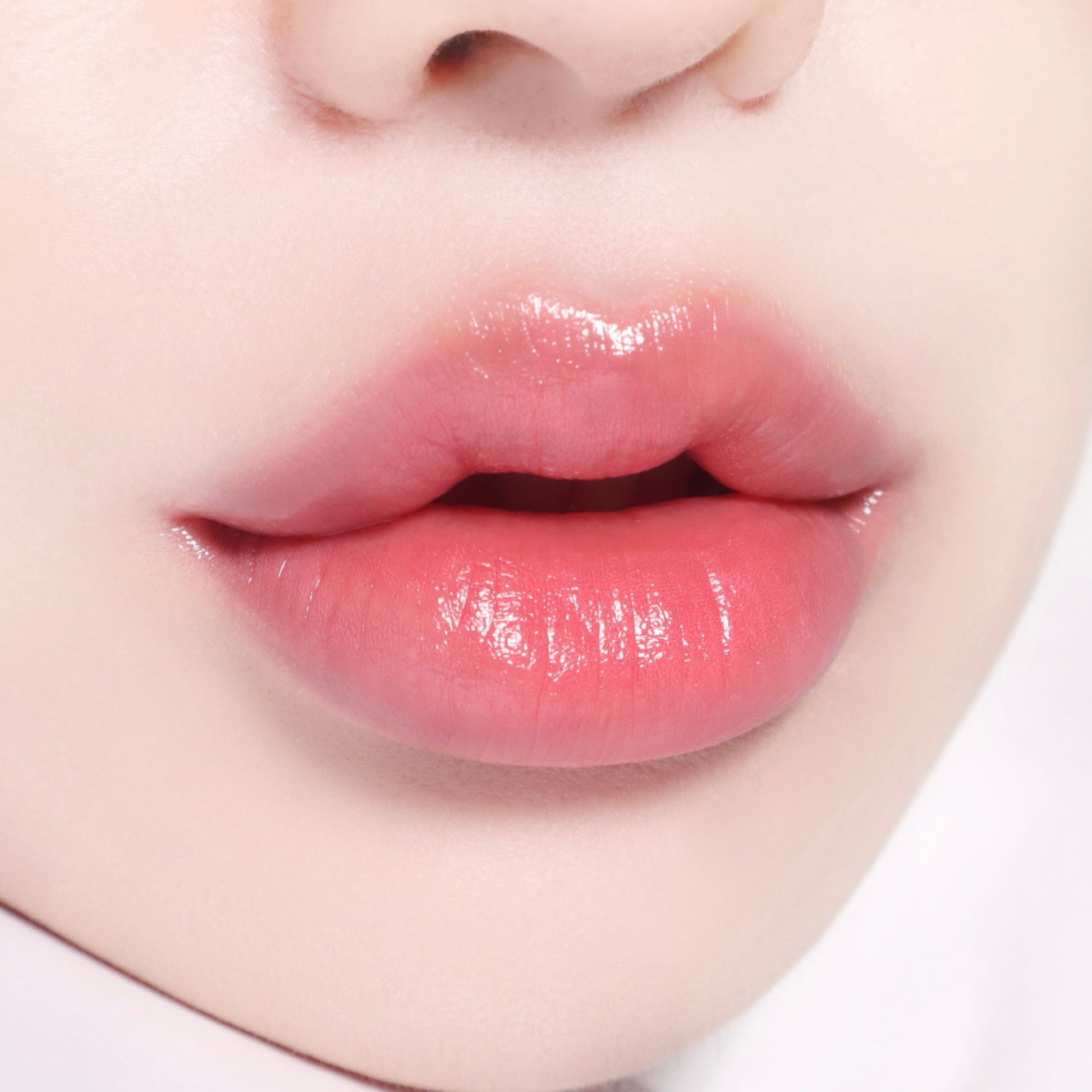 Banila Co B. By Banila Glow Veil Lipstick in Sugar Coral, showing a full lips application with vibrant coral shade