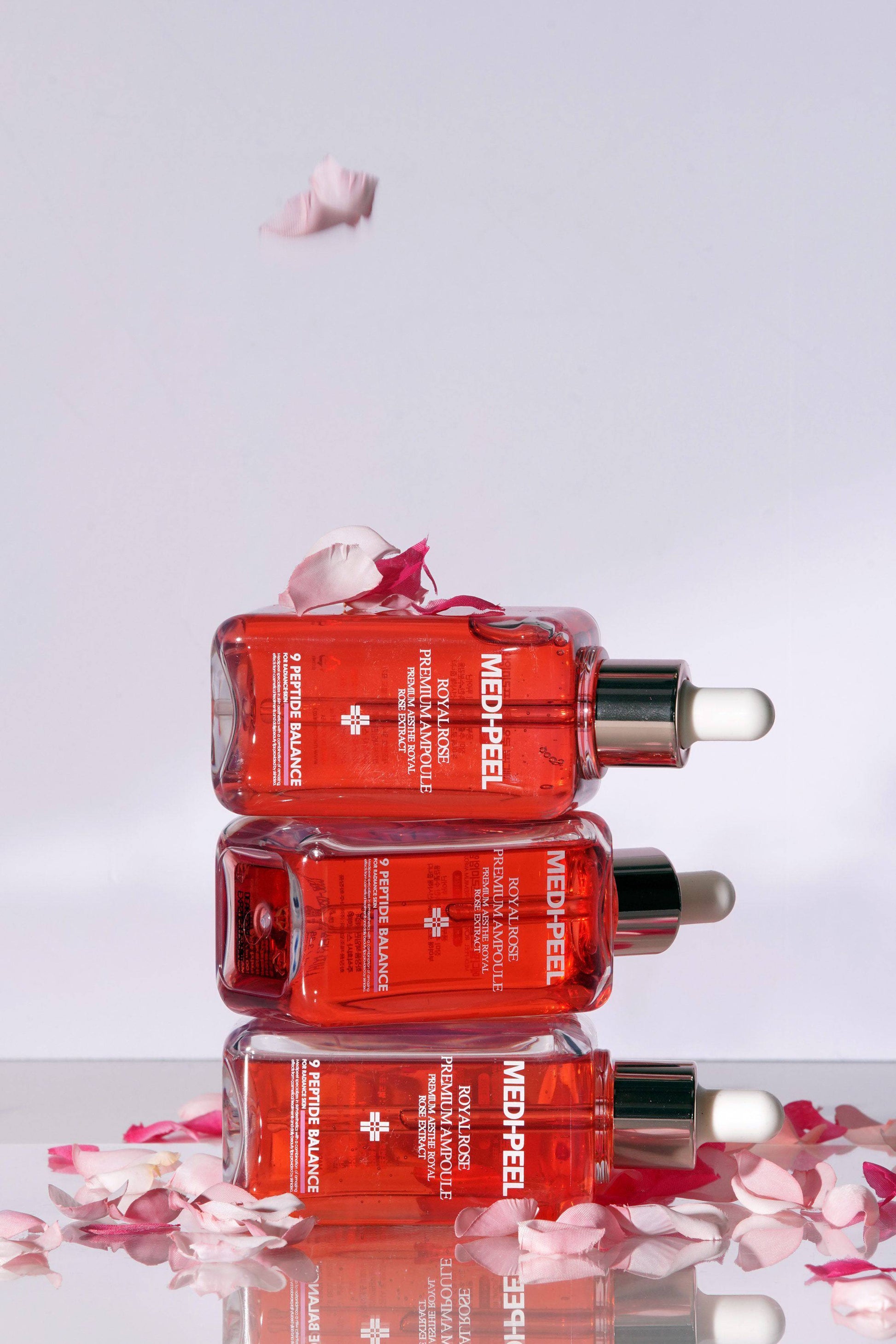 Royal Rose Premium Ampoule by MEDIPEEL+ in a 100ml bottle, showcasing the elegant packaging and clear liquid inside.