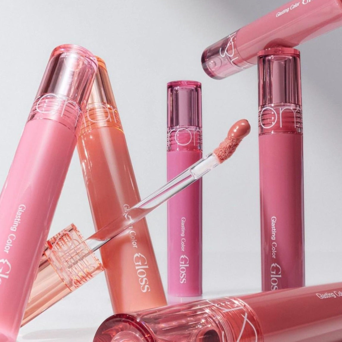 Rom&nd Glasting Color Gloss lip gloss in a vibrant pink shade, featuring a shiny, glossy finish and smooth applicator.