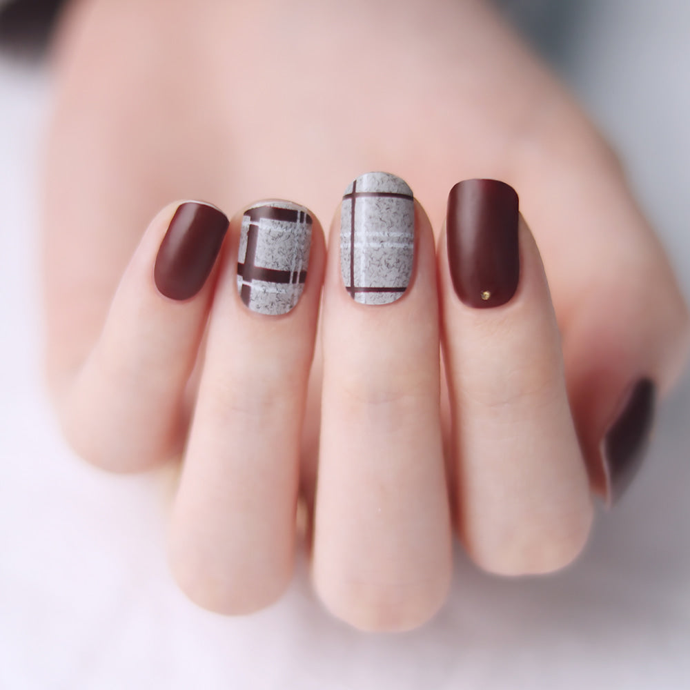 Glossy Blossom Burgundy Velvet Check matte gel nail strips applied on nails with a fashionable checkered design.